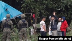 Полски војници покрај група мигранти заглавени на границата меѓу Белорусија и Полска, 1 септември 2021 година