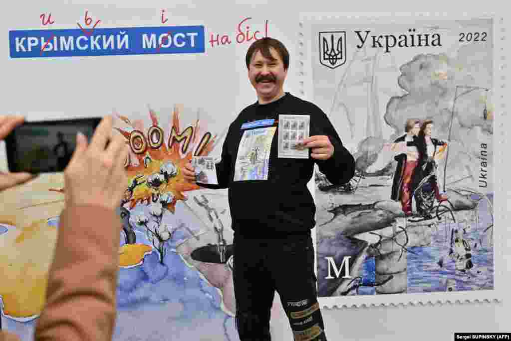 В Киеве покупатель позирует перед плакатом с почтовым конвертом и новой маркой под названием &laquo;Крымский мост на бис&raquo;, в футболке с той же маркой, на главпочтамте 4 ноября 2022 года, в день&nbsp;начала продажи новой марки. Марку, посвященную взрыву на мосту, соединяющем украинский Крым и Российскую Федерацию,&nbsp;ввел в обращение почтовый оператор &laquo;Укрпочта&raquo; &nbsp;