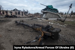 Повреден съветски паметник от Втората световна война, заснет през март сред останките от модерна бронирана машина и разрушени сгради в превзетия град Тростянка, в района на Суми.