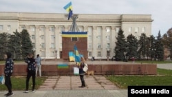 Жители на Херсон снимат флагове на Украйна и Европейския съюз в петък следобяд.