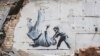 O posibilă lucrare a artistului britanic stradal Banksy pe zidul unei clădiri distruse de lupte la Borodianka, regiunea Kiev, 13 noiembrie 2022.