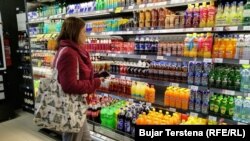 Një konsumatore duke shikuar flamujt e origjinës së produkteve.