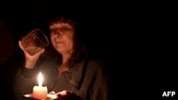 Илустративна фотографија/ Жена во Киев пие вода на свеќа, ноември 2022