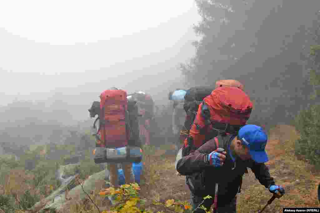 Археологи предварительно разведали разные пути подхода к месту скопления высокогорных петроглифов, куда отправляется экспедиция. Наиболее коротким и наименее энергозатратным для пешего перехода оказался маршрут через горнолыжный курорт &laquo;Ак-Булак&raquo;. Во-первых, он находится в горах и к нему можно подъехать на автотранспорте. Во-вторых, за полчаса канатная дорога доставила до точки, от которой до пункта назначения в среднем два-три часа хода. На фото участники экспедиции в самом начале подъема в верхней части елового леса.