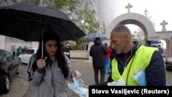 Zaštitar dijeli maske ispred manastira Ostrog, Crna Gora, Arhivska fotografija, 12. maj 2020.