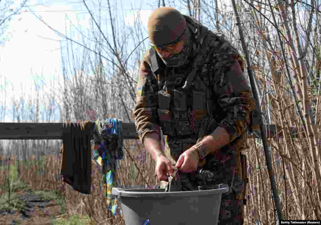 Припадник на украинските вооружени сили пере алишта на линијата на поделба, во близина на градот Доњецк во Украина