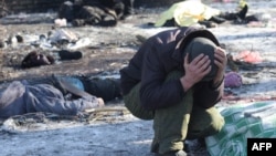 Мъж плаче до тялото на съпругата си, убита в резултат на удара в Донецк 