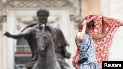 Žena koristi veo da se sakrije od sunca na Kapitolinskom brdu tokom toplotnog talasa širom Italije, u Rimu, 13. jula 2023. 