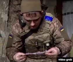 უკრაინელი სამხედრო მოსამსახურე ანდრეი ცდილობს წაიკითხოს ბრძოლის ველზე მოკლული რუსი ჯარისკაცისათვის ნაპოვნი წერილი