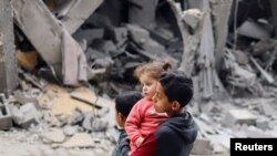 Fëmijë palestinezë afër një zone të shkatërruar në Gazë, si pasojë e konfliktit Izrael-Hamas.