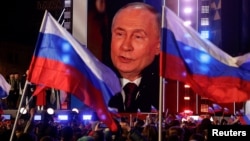 Russian President Vladimir Putin is seen on a screen on the stage as he attends a rally marking the 10th anniversary of Russia's occupation of Ukrainian Crimea, on Red Square in central Moscow on March 18.

