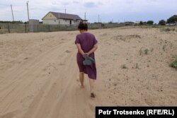 Маржан Махметова идёт по засыпанной песком улице. Село Хан Ордасы, Западно-Казахстанская область. 28 июня 2023 года