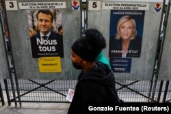 Oameni trecând prin fața unor afișe electorale la Paris, înainte de alegerile prezidențiale franceze din 2022