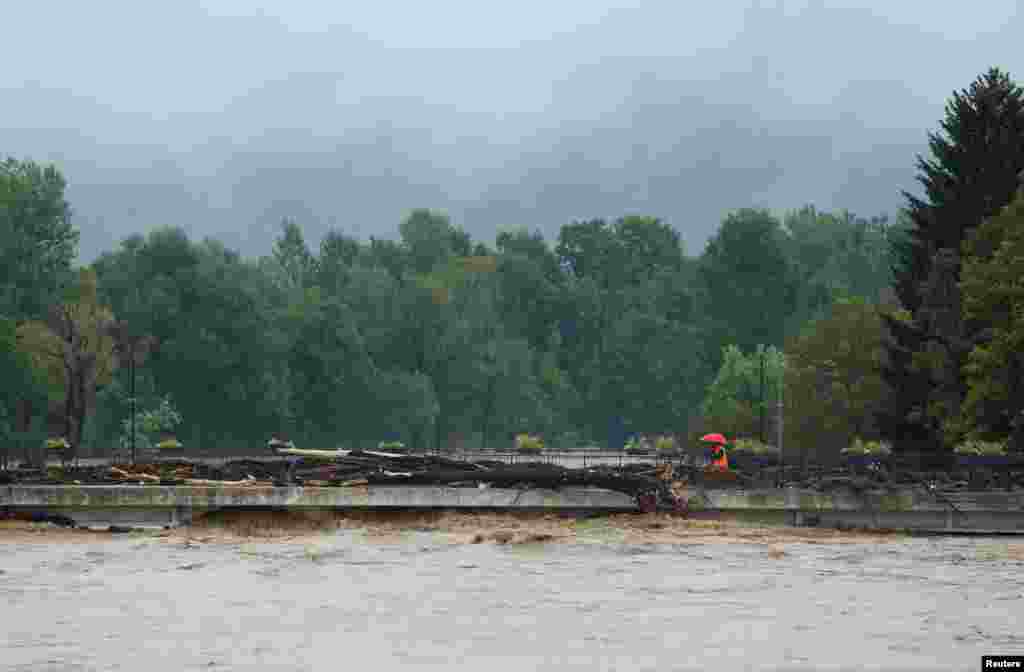 Čovjek hoda preko mosta uz koji su obrušena stabla, Medvode, 4. avgust 2023.
