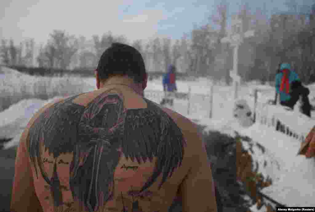 Un bărbat cu un tatuaj pe spate pe malul apelor înghețate de la Mănăstirea Aciairski. Temperaturile au fost de până la -28 de grade Celsius.(foto&nbsp;&nbsp;REUTERS/Alexey Malgavko)