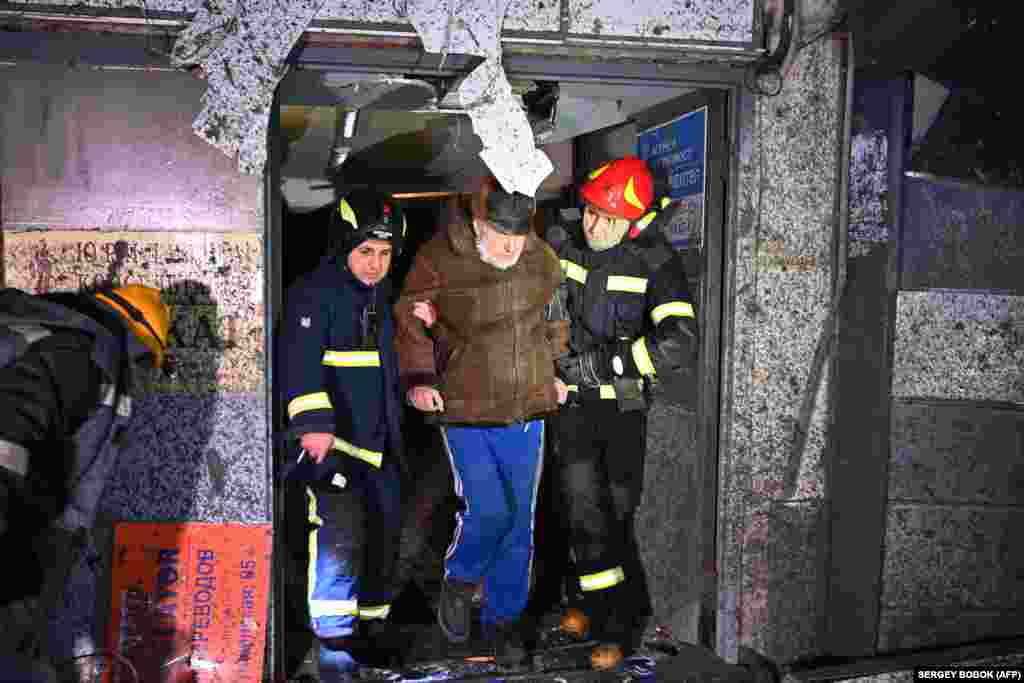 Spasioci pomažu čovjeku da napusti oštećenu stambenu zgradu. Hiljade stanovnika ostale su bez struje nakon što je raniji štrajk oštetio elektroenergetsku infrastrukturu.