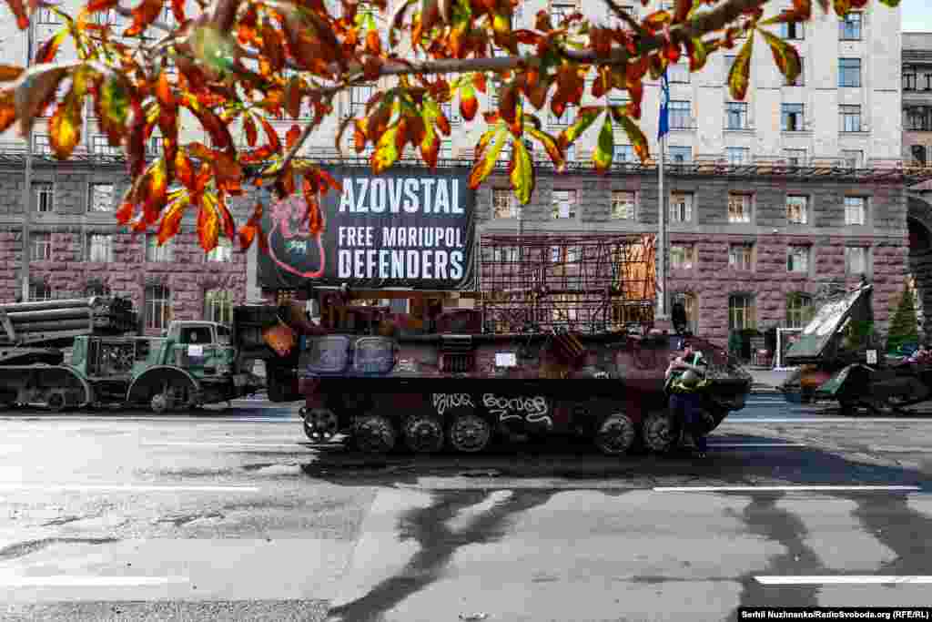 Rămășițele unui blindat rusesc, pe fundalul unui afiș care cere eliberarea din captivitate a apărătorilor de la Mariupol și a uzinei Azovstal. Kiev, 21 august 2023 &nbsp;