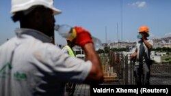 Punëtorë të ndërtimtarisë duke u freskuar me ujë teksa punojnë nën temperatura të larta. Fotografi e 19 qershorit në Prishtinë.