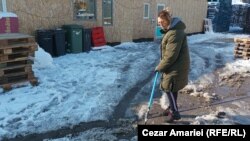La -8 grade Celsius, sinistrata Doina Iliescu curăță curtea casei din Crevedia pentru a avea acces în containerele în care trăiesc aproape jumătate de an, de când casa lor a fost distrusă, în seara zilei de 26 august 2023.
