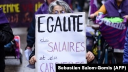 „Egyenlőség a bérekben és karrierben” feliratú plakátot tart egy nő a nemzetközi nőnap alkalmából rendezett tüntetésen Nantes-ben 2023. március 8-án