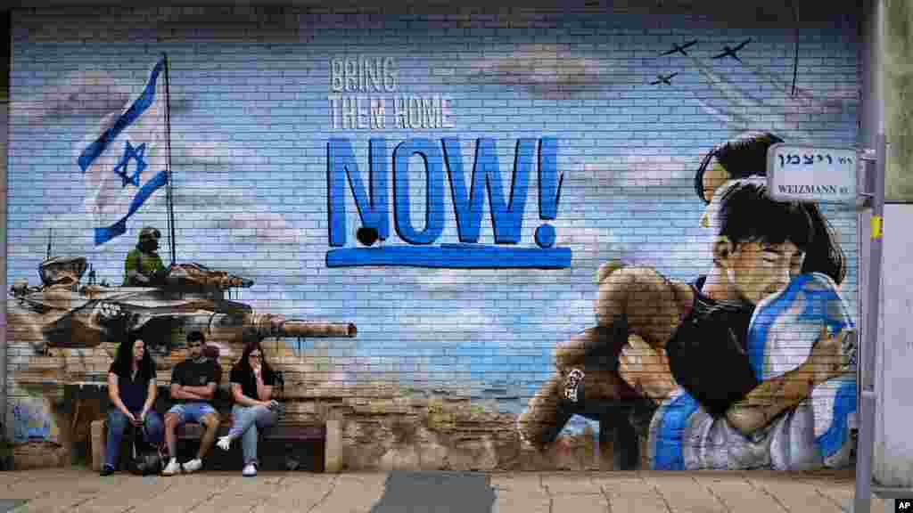 Gyászolók a Hamász október 7-i támadása során elrabolt túszok hazatérését követelő graffiti mellett az izraeli Kfar Szaba temetője előtt 2023. november 12-én