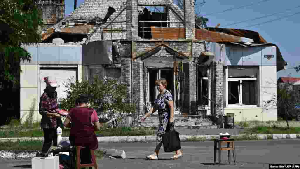 Egy helyi utcai árustól vásárol egy súlyosan megrongálódott épület előtt a kelet-ukrajnai, frontvonal menti Liman városában július 17-én. Olekszandr Szirszkij tábornok, az ukrán szárazföldi csapatok parancsnoka július 18-án Telegramon közölte: katonáiknak újabb kihívásokkal kell szembenézniük, miközben továbbra is sikereket könyvelhetnek el az ellentámadásban