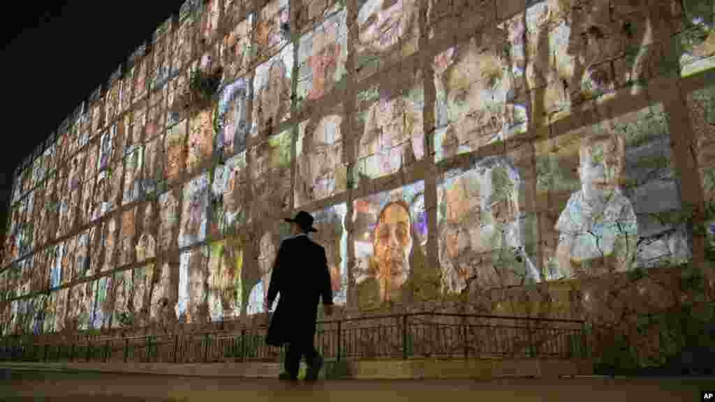 A Hamász által fogva tartott izraeli túszok fényképeit vetítik Jeruzsálem óvárosának falára 2023. november 6-án. A Hamászt, amelyet többek közt az&nbsp;Európai&nbsp;Unió és az Egyesült&nbsp;Államok is terrorszervezetnek minősít, ezernégyszáz embert ölt meg és kétszáznegyven másikat rabolt el október 7-én