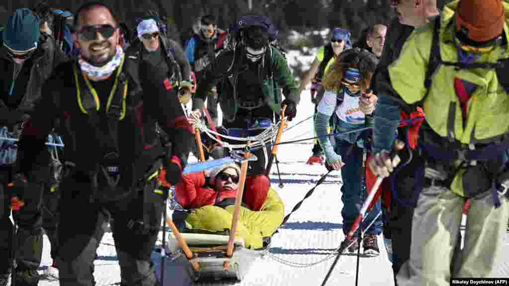 Volonteri vuku Aleksandru Aleksandrovu, koja ima cerebralnu paralizu, u sankama uz planinu Rila. Doychinova je rekla da je zimski uspon na Rilu bio posebno izazovan jer su imali samo troje sanki i petoro osoba sa invaliditetom koje su se nadale usponu. &quot;Neki od dobrovoljaca morali su dva puta ići na planinu, vukući sanke.&quot;