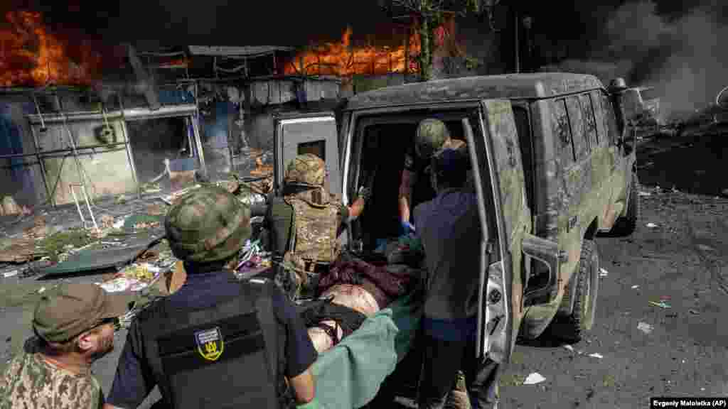 Egy sérült férfit tesznek be a mentőautóba, a háttérben a tragédia helyszíne. Zelenszkij elnök elítélte az ukrajnai Kosztyantyinivka &bdquo;békés város elleni szándékos támadást&rdquo; &nbsp;