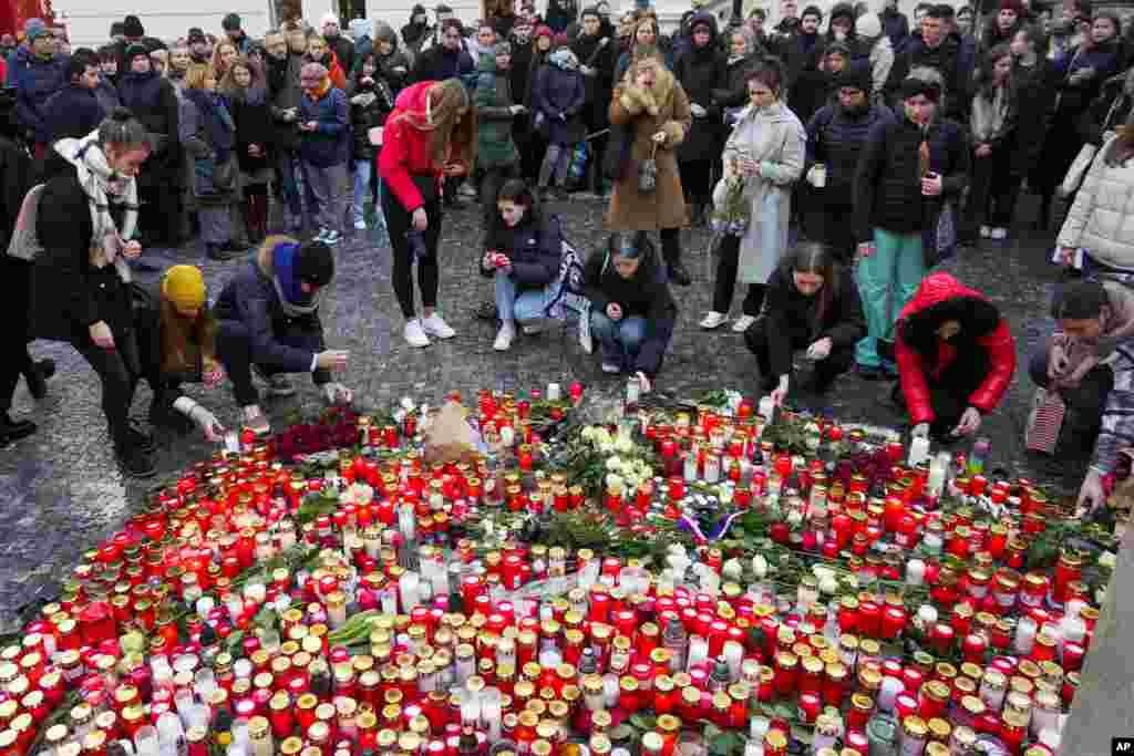 Ljudi pale svijeće ispred zgrade Karlovog univerziteta, mjesta masovne pucnjave u kojoj je stradalo 14 osoba, Prag, 22. decembra 2023.
