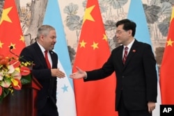Honduraški ministar vanjskih poslova Eduardo Enrique Reina Garcia, lijevo, i kineski ministar vanjskih poslova Qin Gang rukuju se nakon uspostave diplomatskih odnosa između dviju zemalja, tokom zajedničke izjave nakon ceremonije u Diaoyutai State Guesthouseu u Pekingu u nedjelju, 26. marta 2023.