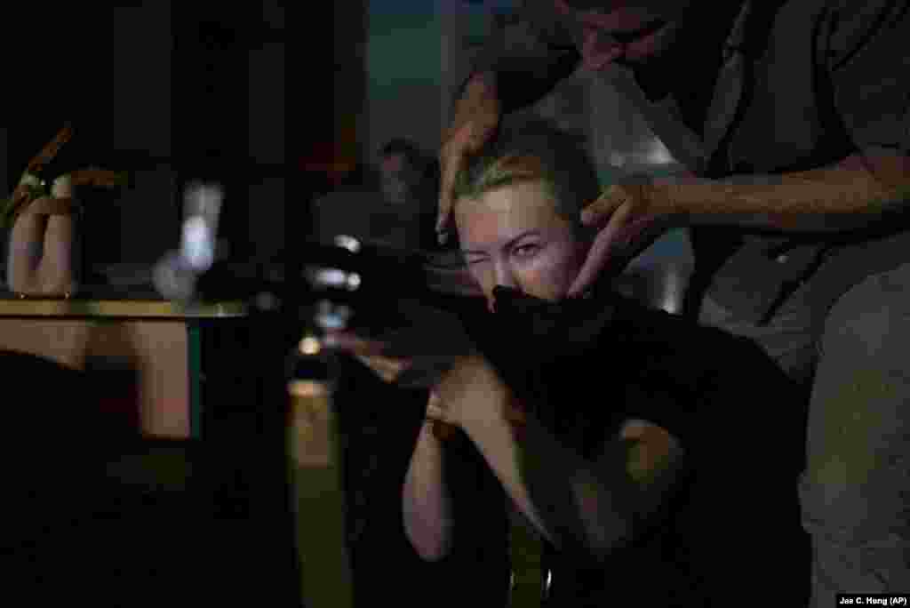 Një instruktor duke drejtuar qëndrimin e një gruaje, e cila është duke e mbajtur një pushkë AK-47 gjatë trajnimit për gjuajtje me armë zjarri. &quot;Qëllimi kryesor këtu është që t&#39;i mësojmë njerëzit se si të mbijetojnë dhe t&#39;u përgjigjen këtyre kërcënimeve ushtarake që ekzistojnë&quot;, shpjegoi Shcherbyna. Autoritetet lokale po shpresojnë se kështu duke i trajnuar njerëzit, do të parandalojnë numrin e viktimave në të ardhmen.