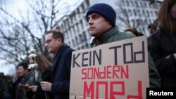 Мъж държи плакат с надпис "Не смърт, а убийство" пред посолството на Русия в Берлин, Германия.