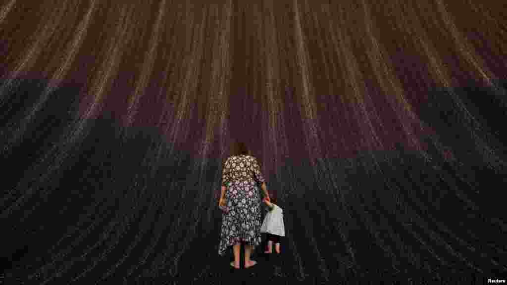 Egy nő kisgyermekkel a COP28 konferenciájának egyik installációjánál&nbsp;Dubajban.&nbsp;Több ország képviselője szerint a felhígított szövegezésű javaslat nem foglalkozik a párizsi megállapodás azon céljával, hogy a felmelegedést 1,5 Celsius-fokra korlátozzák az éghajlatváltozás legsúlyosabb hatásainak elhárítása érdekében. A Föld úton van afelé, hogy megdöntse a legmelegebb év rekordját, ami veszélyezteti az emberi egészséget, és egyre költségesebb és halálosabb szélsőséges időjáráshoz vezet