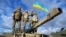 Украинские военнослужащие держат украинский флаг, позируя на танке Challenger 2 во время учений в лагере Бовингтон на юго-западе Великобритании. 22 февраля 2023 года
