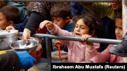 Palesztin gyerekek várnak ételre Rafahban 2024. február 13-án
