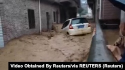 Čovjek gleda u automobil koji je zatrpala brza poplavna voda, u selu Fuyuan, okrug Guangning, Kina, fotografija preuzeta iz video snimka sa društvenih medija od 19. aprila 2024. 