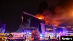 Az orosz mentőszolgálatok járművei parkolnak az égő Crocus City Hall koncerthelyszín közelében, Moszkva mellett 2024. március 22-én