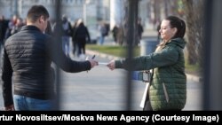 Мужчине в России вручают листовку с призывом идти на службу в армию