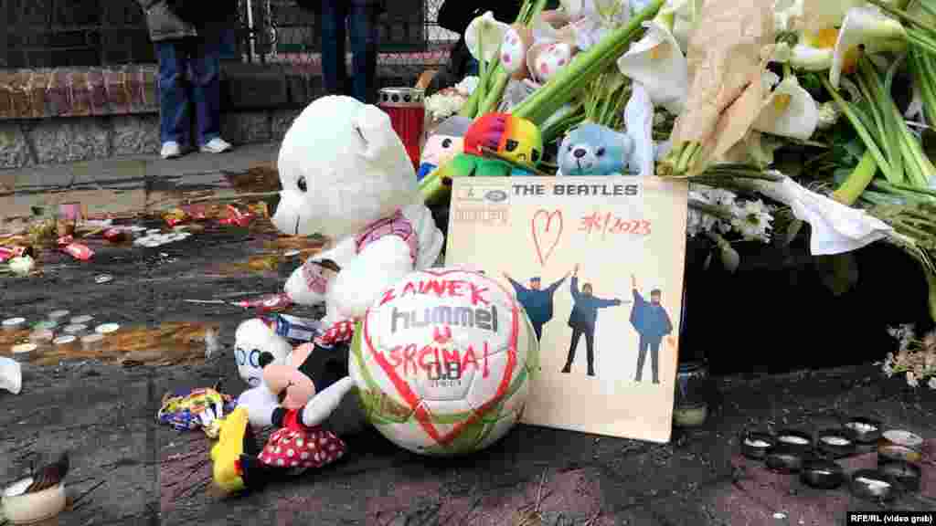 Pored cveća i plišanih igračaka, lopta sa porukom &quot;zauvek u srcima&quot;.