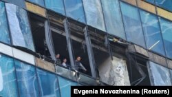 უსაფრთხოების სამსახურების წარმომადგენლები იკვლევენ დრონების თავდასხმით დაზიანებულ საოფისე შენობას მოსკოვში (2023 წლის 1 აგვისტო). მოსკოვში უპილოტოების ბოლო შეტევას კრემლის ნერვული რეაქცია მოჰყვა.