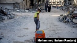 Момче дърпа количка сред разрушенията на втория по големина град в Ивицата Газ Хан Юнис