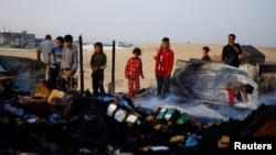 Деца стоят сред останките от палатки и временни подслони, които бяха ударени при израелска атака в нощта в неделя срещу понеделник в Рафах, Ивицата Газа.