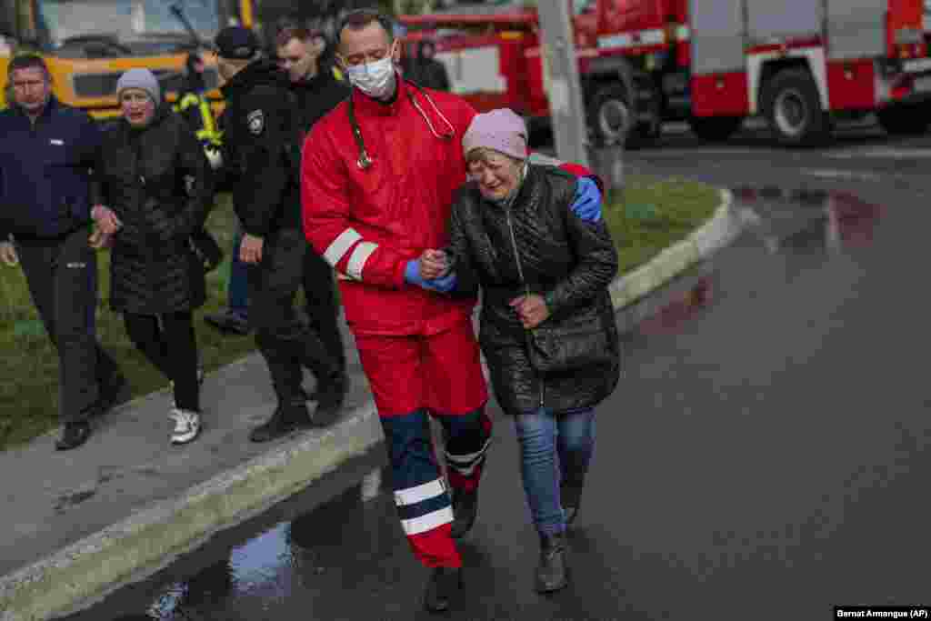 A rescue worker helps a crying woman in Uman.