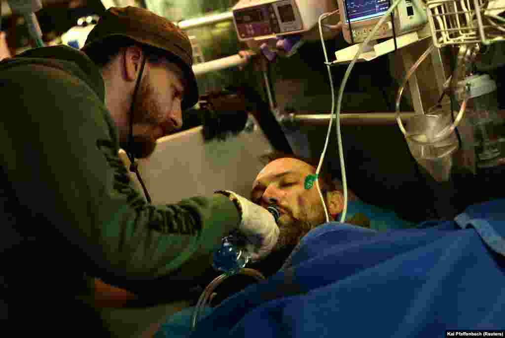 Ruslani, një ndihmës vullnetar 26-vjeçar, i jep për të pirë një ushtari ukrainas që u plagos në Bahmut.