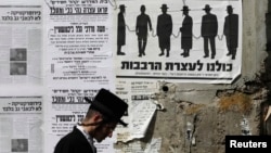 Haredi Jevrej prolazi pored uličnog plakata u jerusalimskoj četvrti Mea Šearim kojim se poziva na protest protiv vladinih planova da privuče više ultraortodoksnih muškaraca u vojsku, 3. juna 2013.