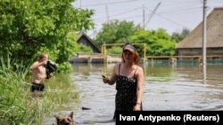 Локалните жители шетаат по поплавена улица за време на евакуација од поплавеното подрачје по пробивањето на браната Нова Каховка, среде рускиот напад врз Украина, во Херсон, Украина, 7 јуни 2023 година.