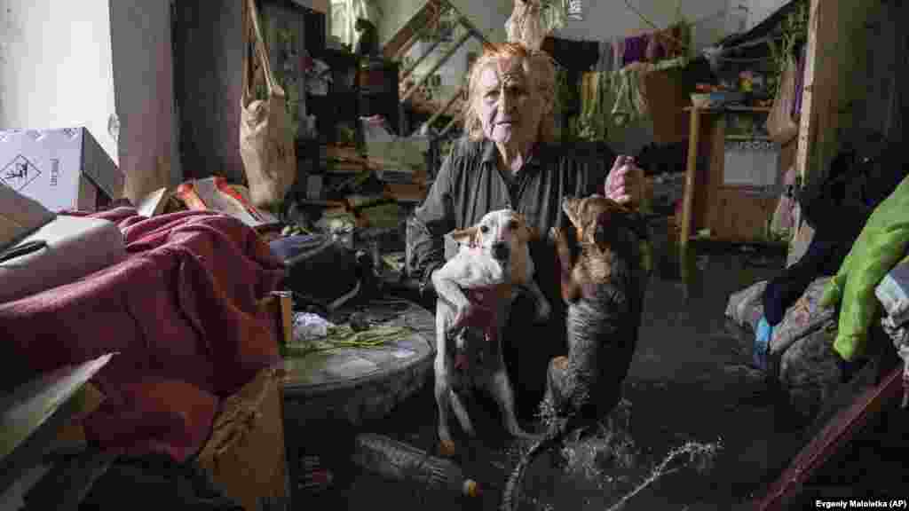 Tetyana, egy helyi, a gátrobbanás következtében elárasztott otthonában kutyáival az ukrajnai Herszonban június 6-án &nbsp;