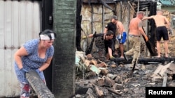 Helyiek dolgoznak az orosz erők által lebombázott épületeknél egy Kijevhez közeli településen 2023. augusztus 30-án