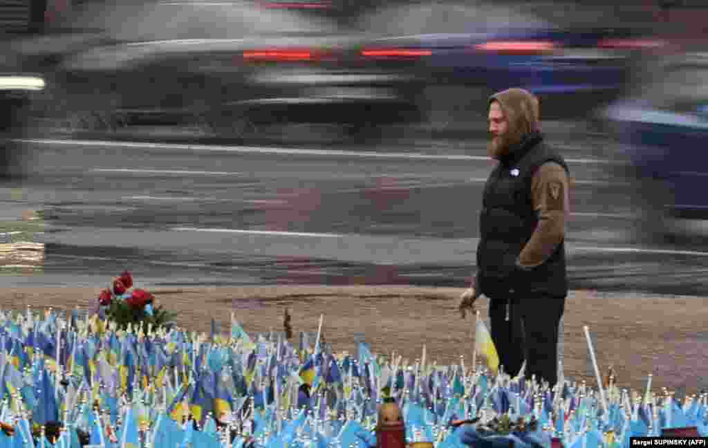 Čovek ispred improvizovanog spomenika poginulim ukrajinskim vojnicima pod jakom kišom na Trgu nezavisnosti u Kijevu.